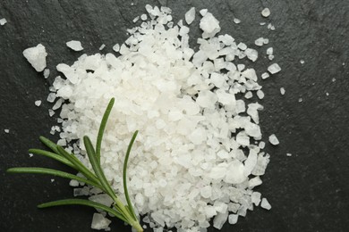 Photo of Sea salt and rosemary on dark gray textured table, top view