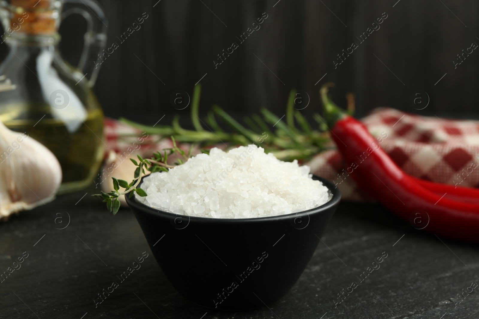 Photo of Sea salt and thyme in bowl on dark gray textured table