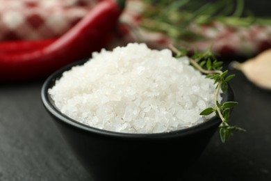 Photo of Sea salt and thyme in bowl on dark gray table, closeup