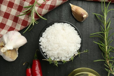 Photo of Sea salt and spices on dark gray textured table, flat lay