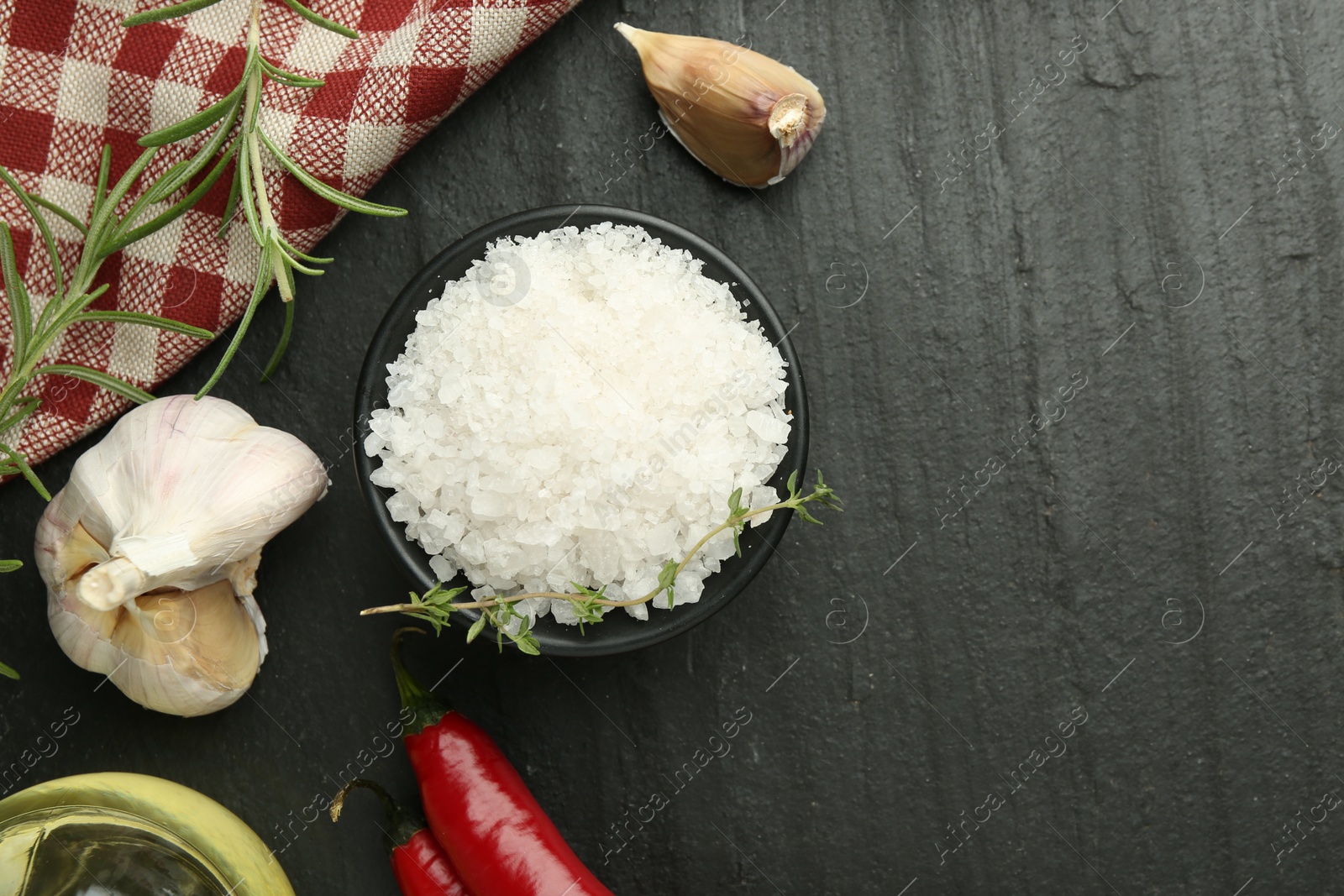 Photo of Sea salt and spices on dark gray textured table, flat lay. Space for text