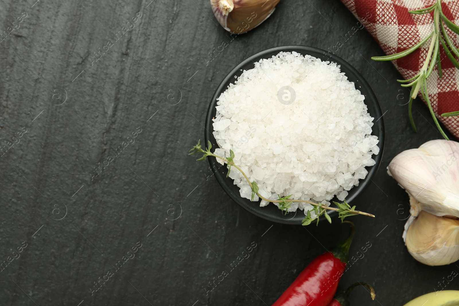 Photo of Sea salt and spices on dark gray textured table, flat lay. Space for text