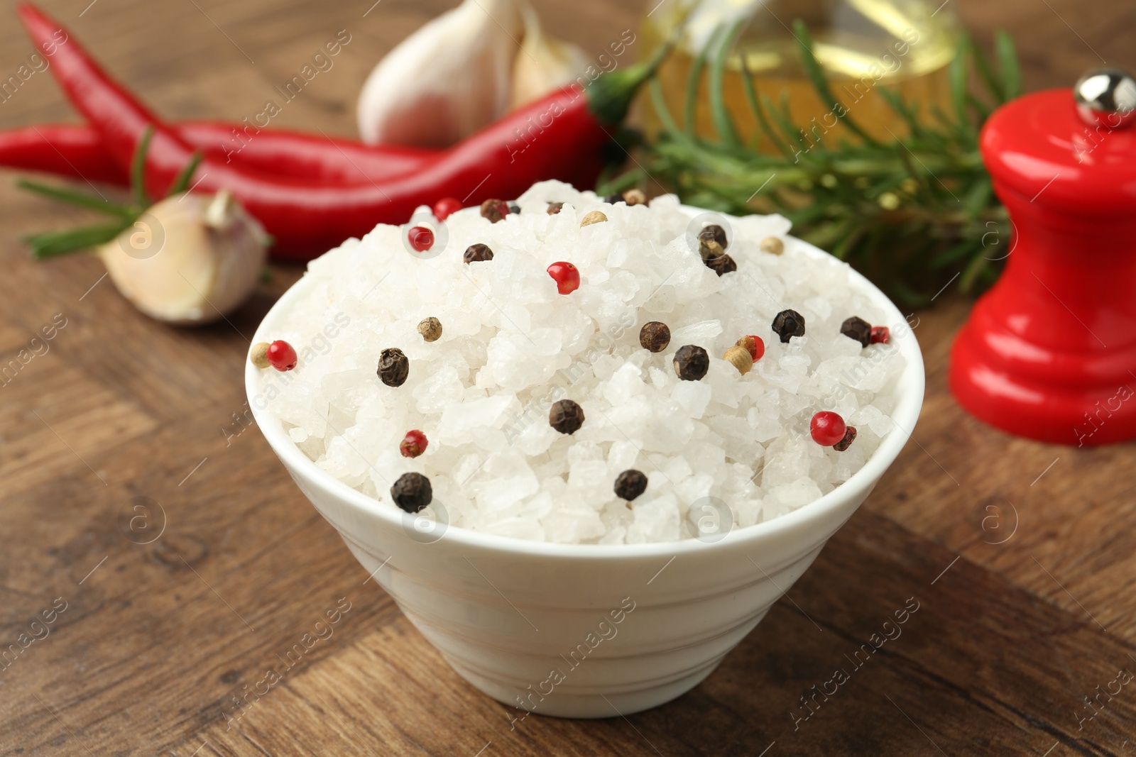 Photo of Sea salt and spices in bowl on wooden table, closeup