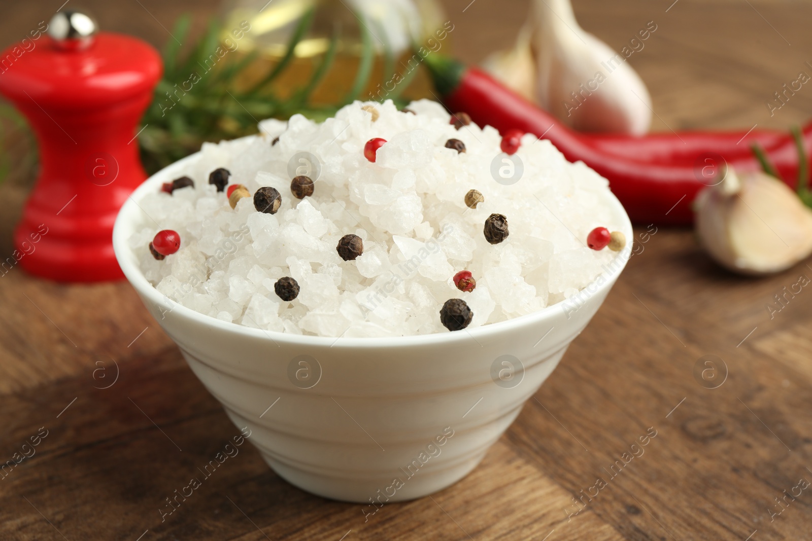 Photo of Sea salt and spices in bowl on wooden table, closeup