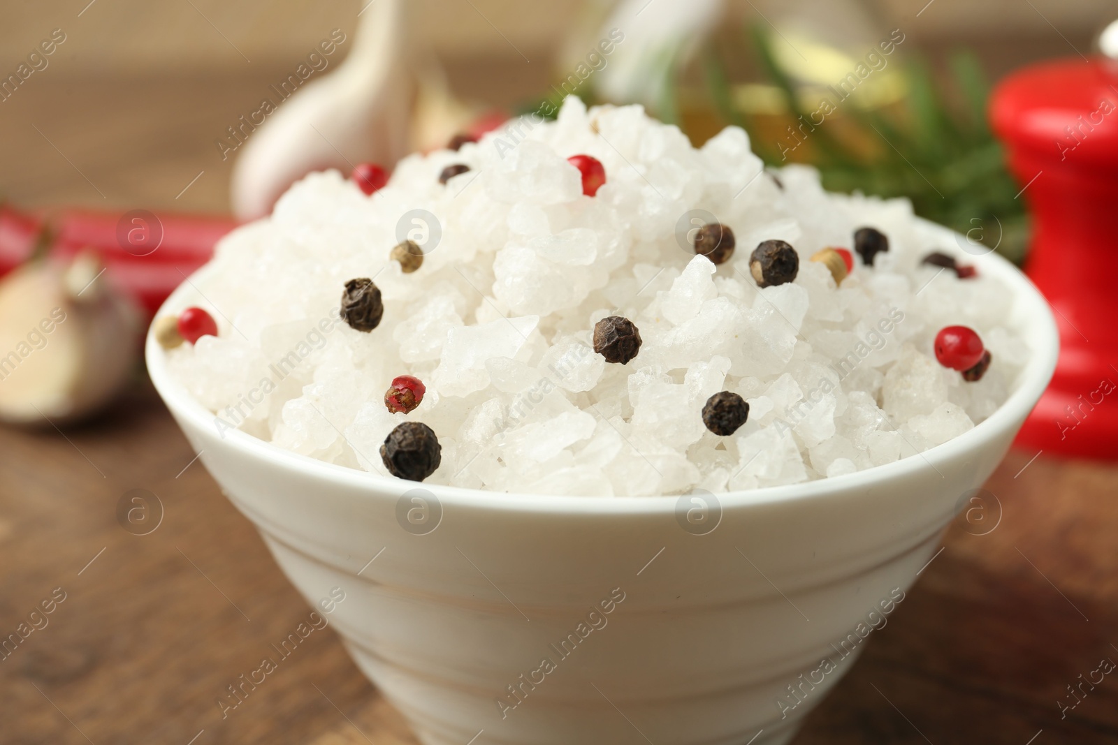 Photo of Sea salt and spices in bowl on brown table, closeup