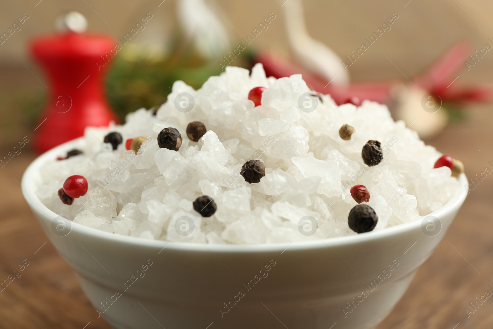 Photo of Sea salt and spices in bowl on brown table, closeup