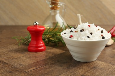 Photo of Sea salt in bowl and spices on wooden table, closeup