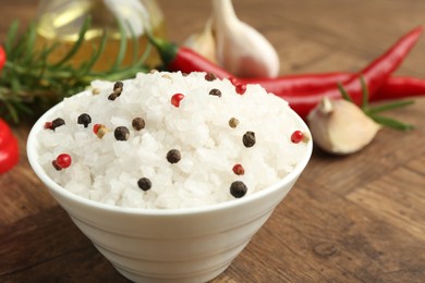 Photo of Sea salt in bowl and spices on wooden table, closeup