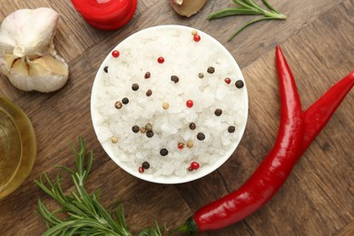 Sea salt in bowl and spices on wooden table, flat lay