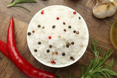 Photo of Sea salt in bowl and spices on wooden table, flat lay