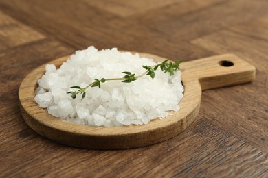 Photo of Sea salt and thyme on wooden table, closeup