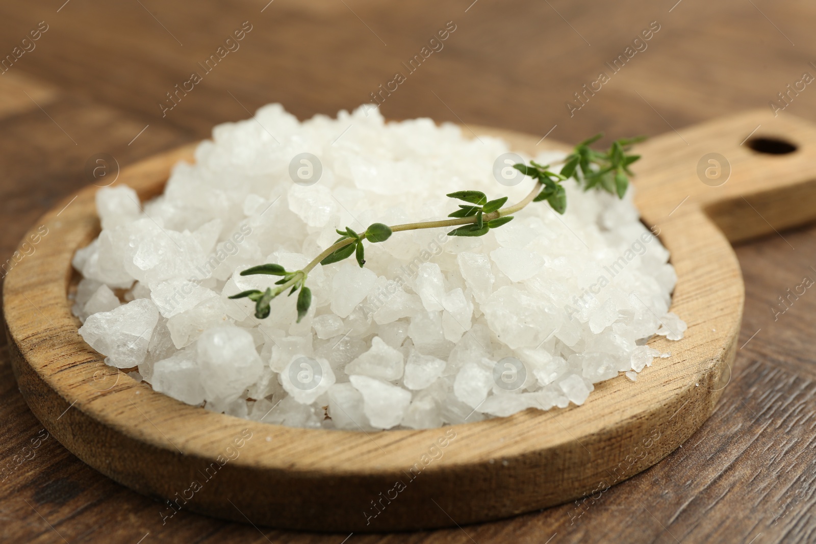 Photo of Sea salt and thyme on wooden table, closeup