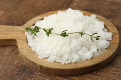 Photo of Sea salt and thyme on wooden table, closeup