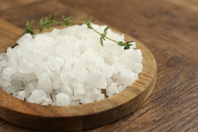 Photo of Sea salt and thyme on wooden table, closeup