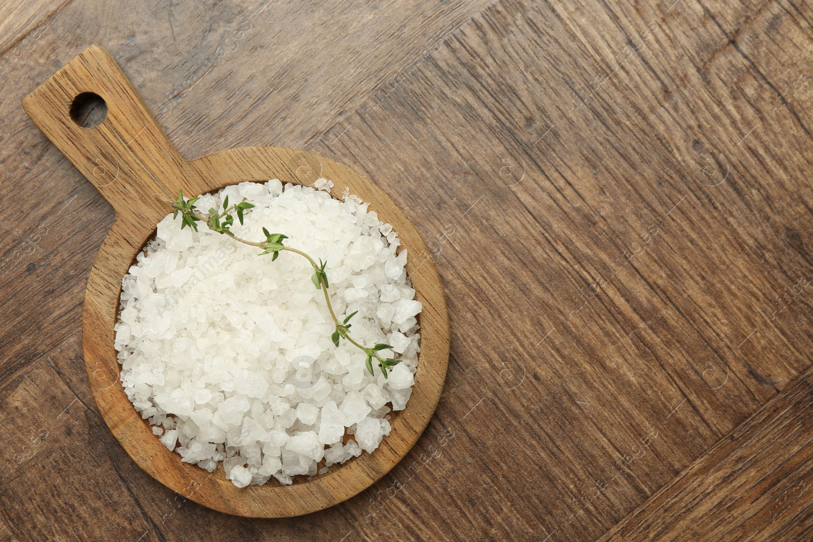 Photo of Sea salt and thyme on wooden table, top view. Space for text