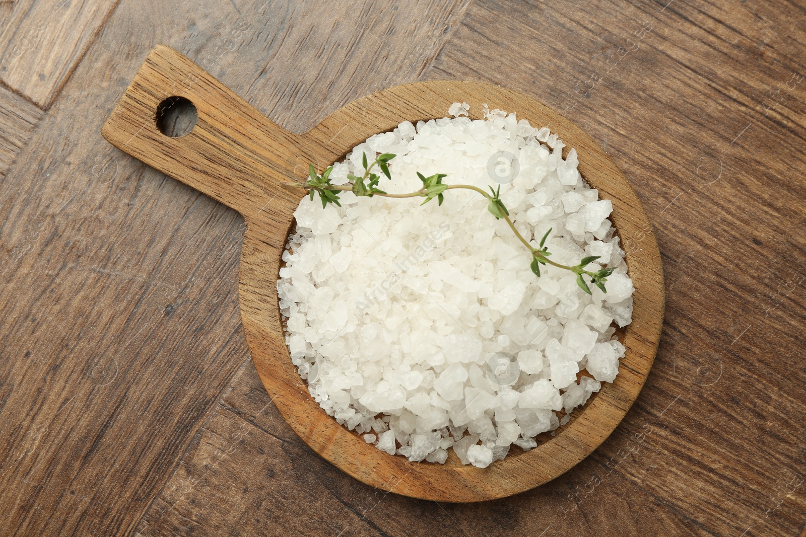 Photo of Sea salt and thyme on wooden table, top view