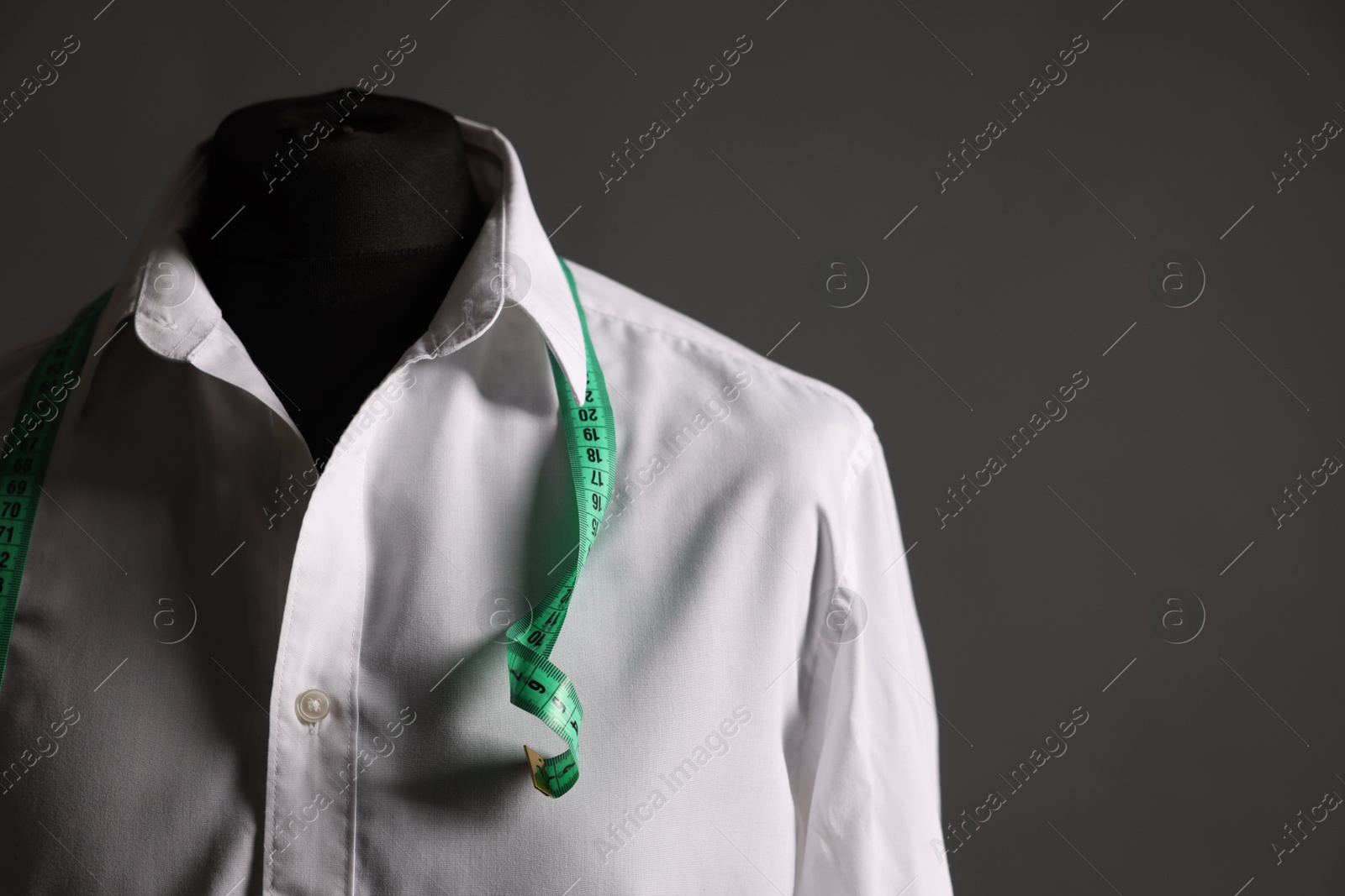 Photo of Male mannequin with white shirt and measuring tape on grey background. Space for text