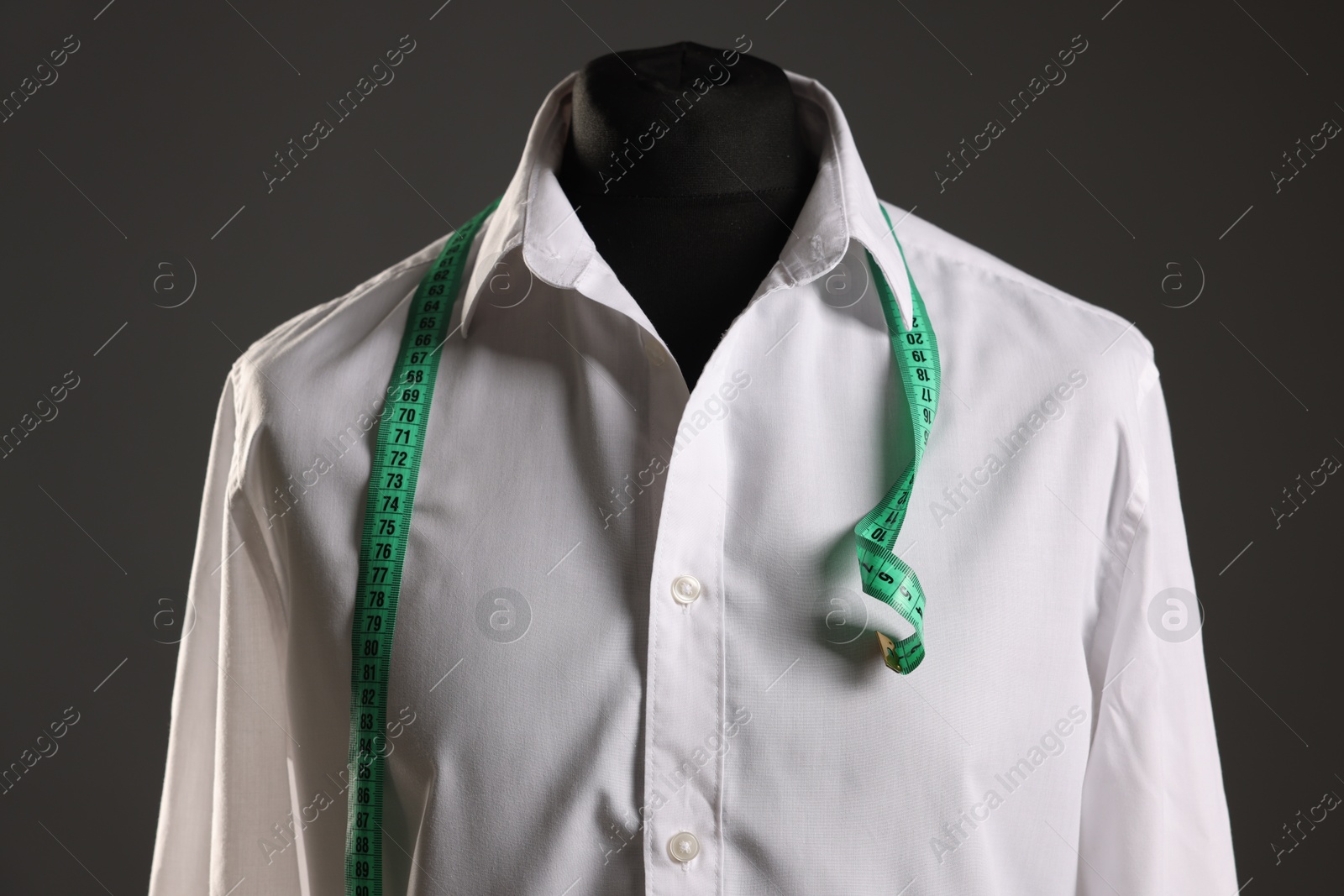 Photo of Male mannequin with white shirt and measuring tape on grey background