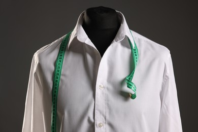 Male mannequin with white shirt and measuring tape on grey background