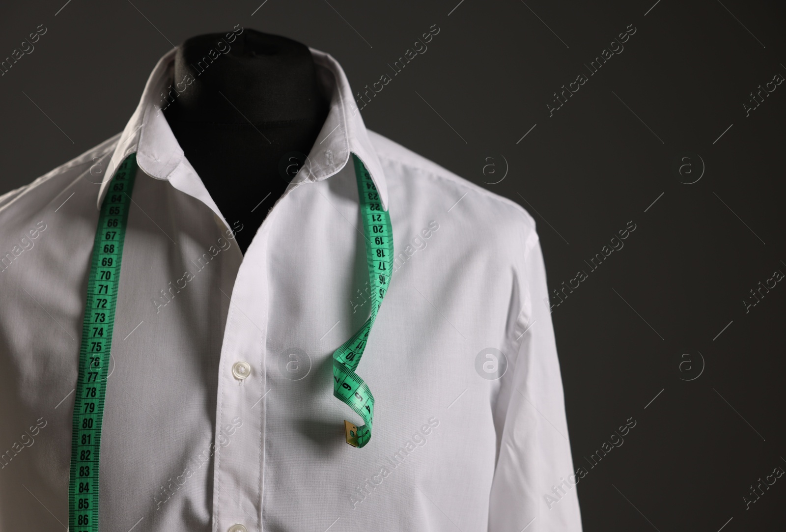 Photo of Male mannequin with white shirt and measuring tape on grey background. Space for text