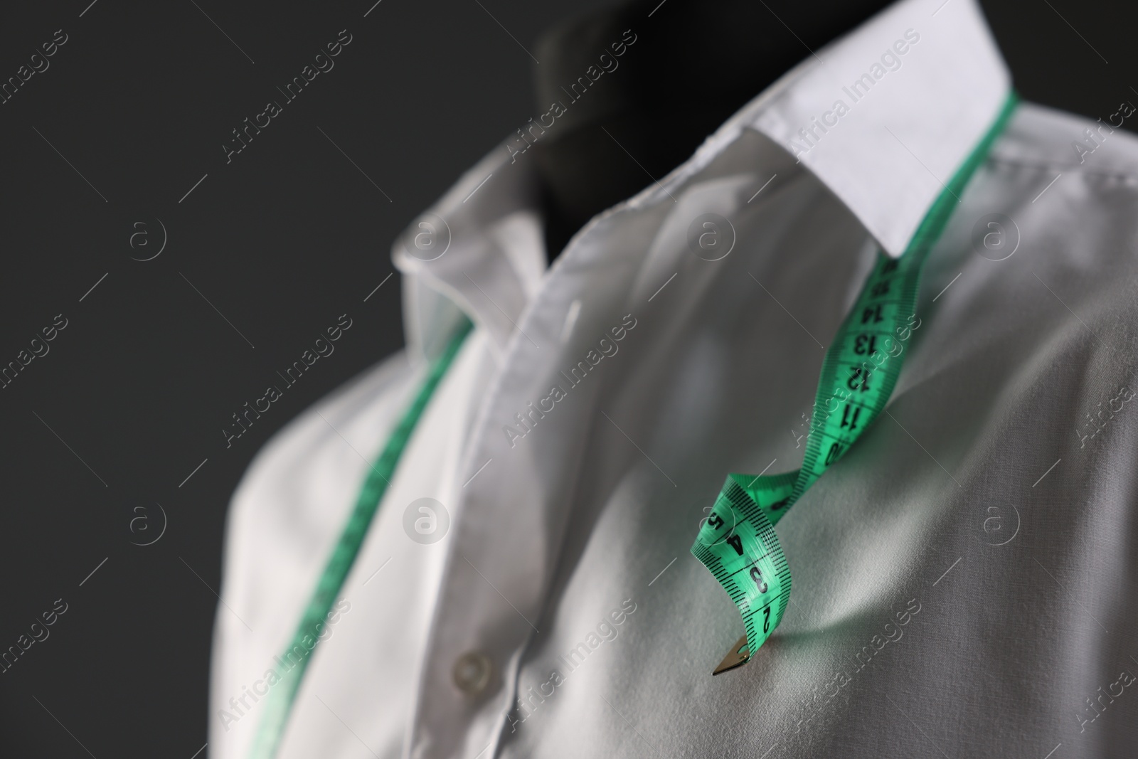 Photo of Male mannequin with white shirt and measuring tape on grey background, closeup