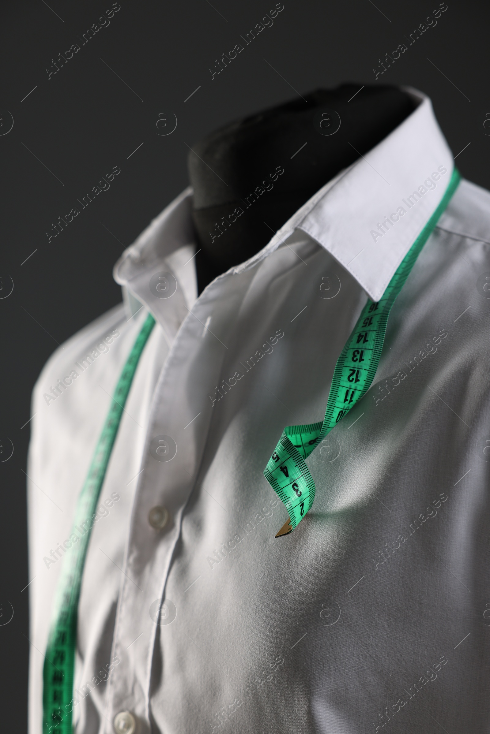 Photo of Male mannequin with white shirt and measuring tape on grey background, closeup