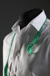 Male mannequin with white shirt and measuring tape on grey background, closeup