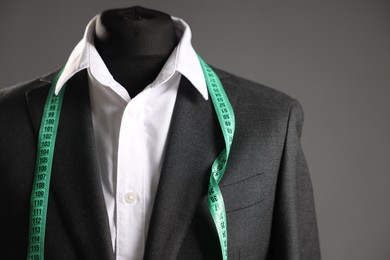 Photo of Male mannequin with jacket, white shirt and measuring tape on grey background