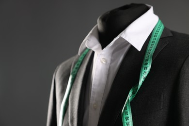 Photo of Male mannequin with jacket, white shirt and measuring tape on grey background, closeup