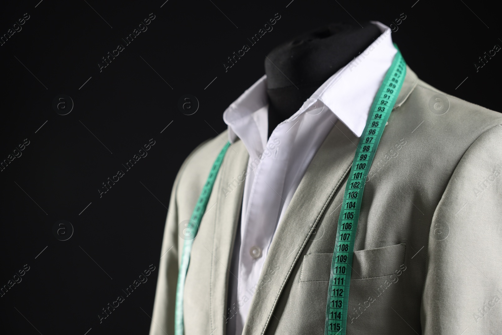 Photo of Male mannequin with jacket, white shirt and measuring tape on black background, closeup. Space for text