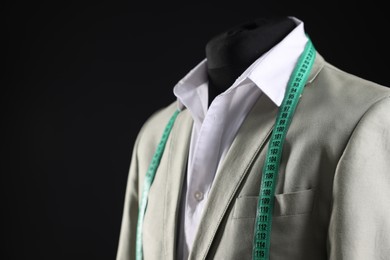 Male mannequin with jacket, white shirt and measuring tape on black background, closeup. Space for text