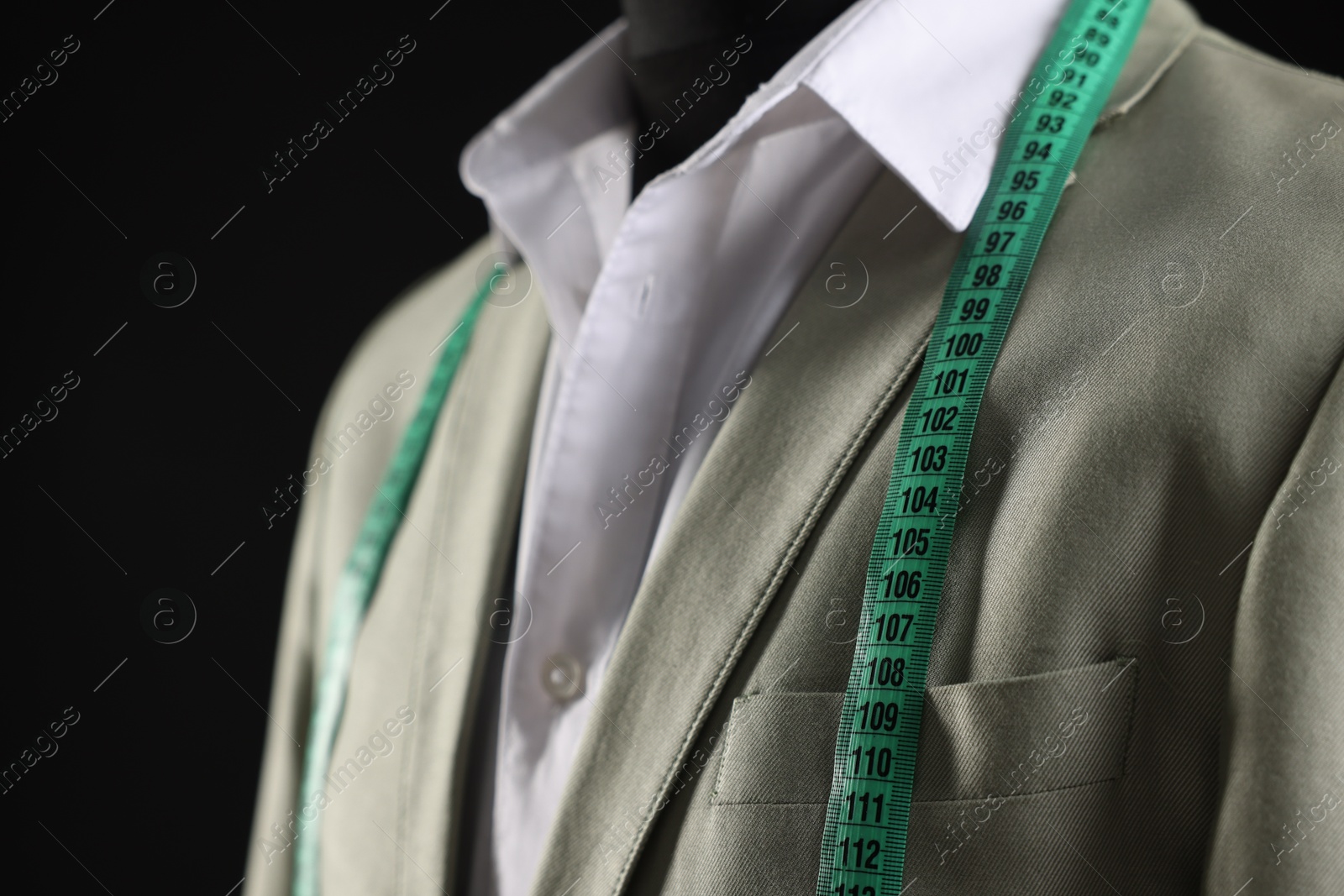 Photo of Male mannequin with jacket, shirt and measuring tape on black background, closeup