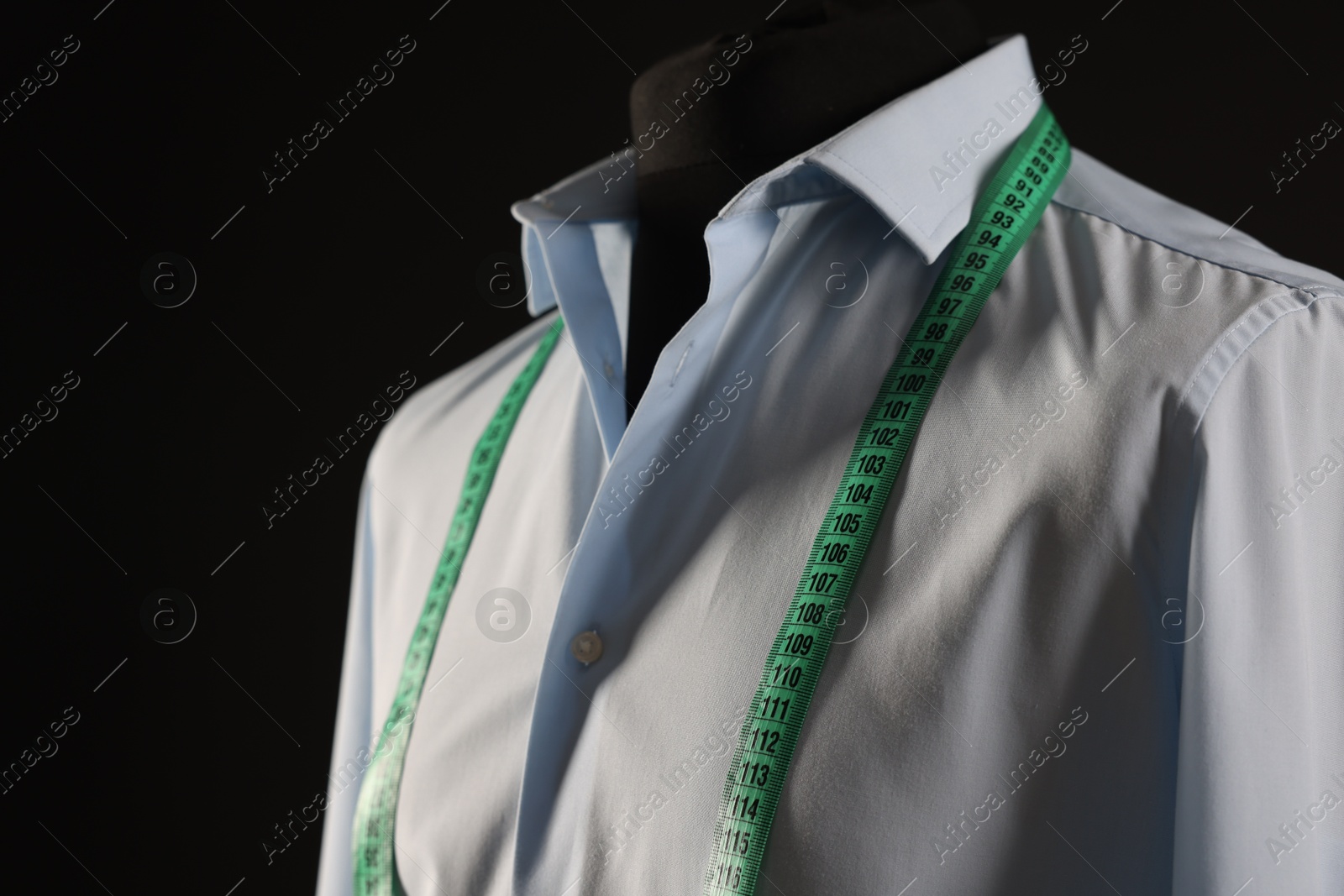 Photo of Male mannequin with shirt and measuring tape on black background, closeup