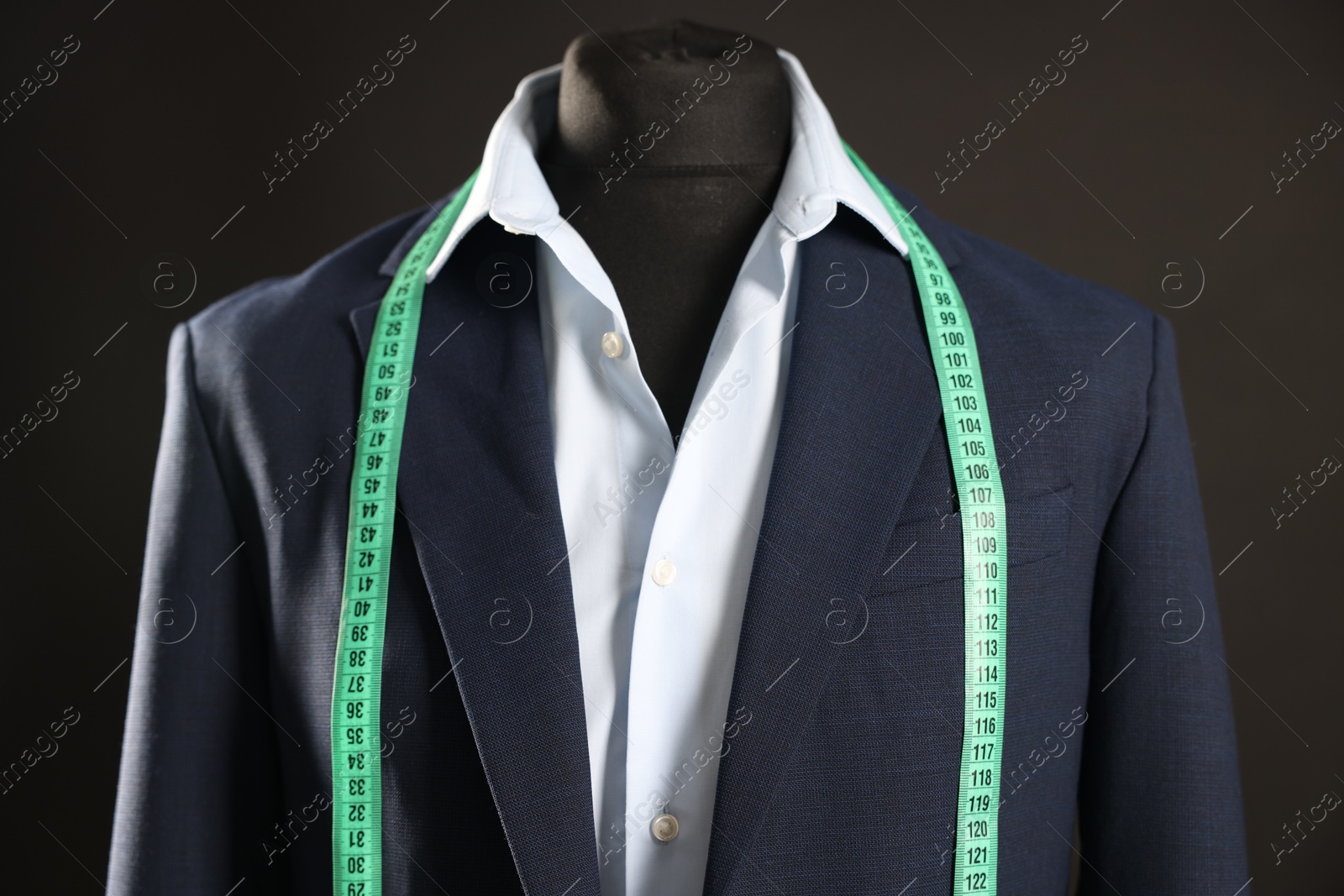 Photo of Male mannequin with jacket, shirt and measuring tape on black background