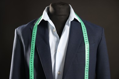 Male mannequin with jacket, shirt and measuring tape on black background