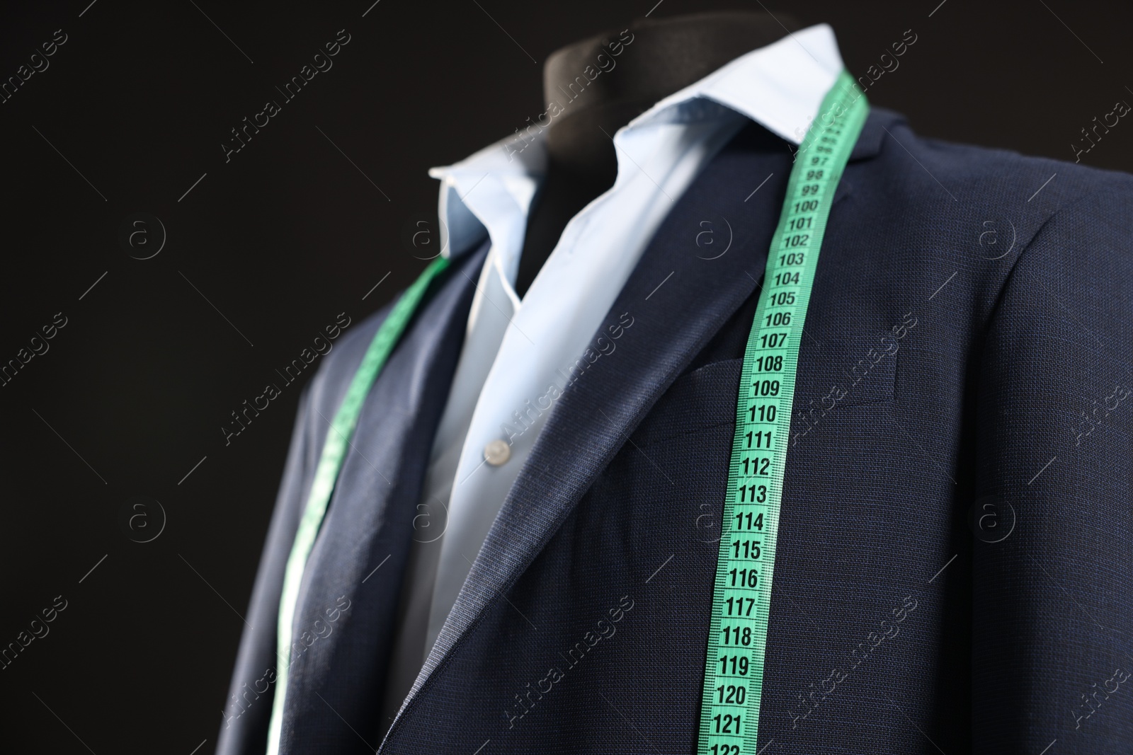 Photo of Male mannequin with jacket, shirt and measuring tape on black background, closeup