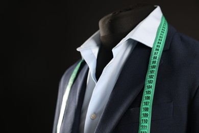 Photo of Male mannequin with jacket, shirt and measuring tape on black background, closeup