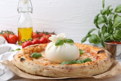 Photo of Delicious pizza with burrata cheese, basil, sauce and tomatoes on table, closeup