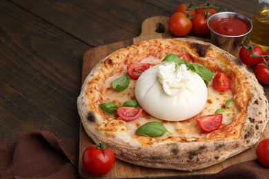 Delicious pizza with burrata cheese, basil, sauce and tomatoes on wooden table, closeup