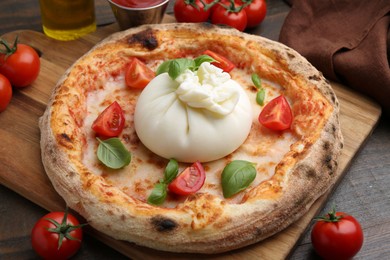 Photo of Delicious pizza with burrata cheese, basil and tomatoes on wooden table, closeup