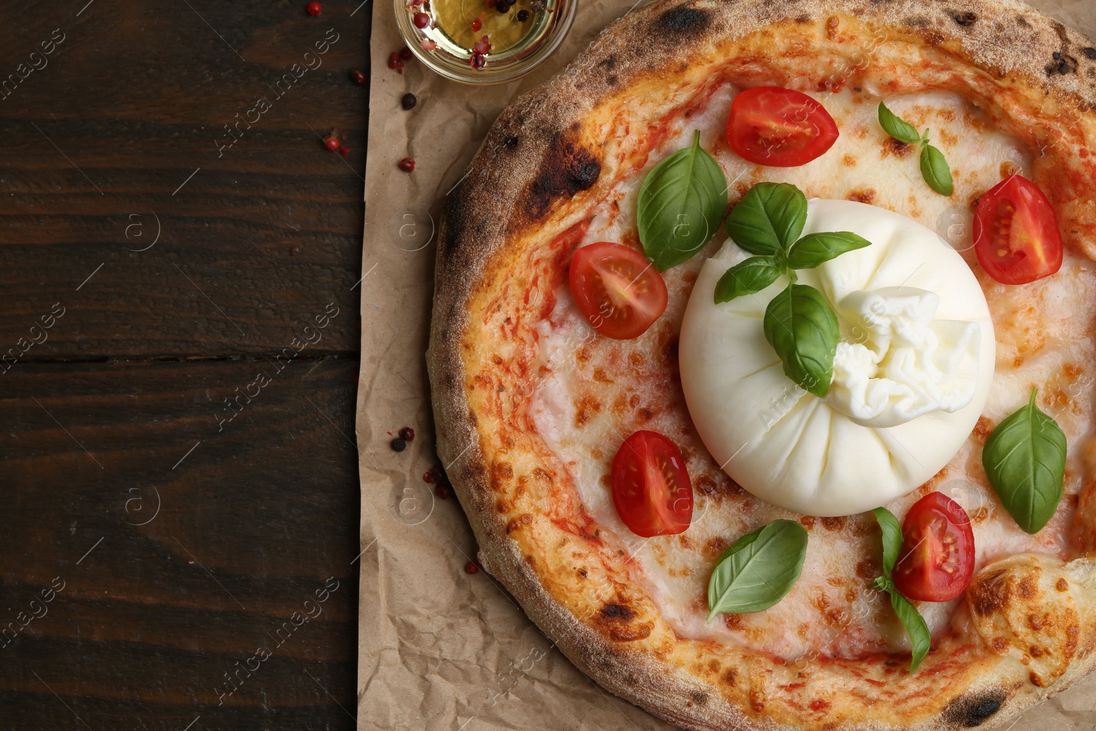 Photo of Delicious pizza with burrata cheese, basil and tomatoes on wooden table, top view