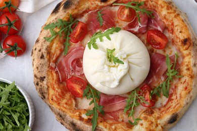 Delicious pizza with burrata cheese, arugula, tomatoes and ham on table, top view