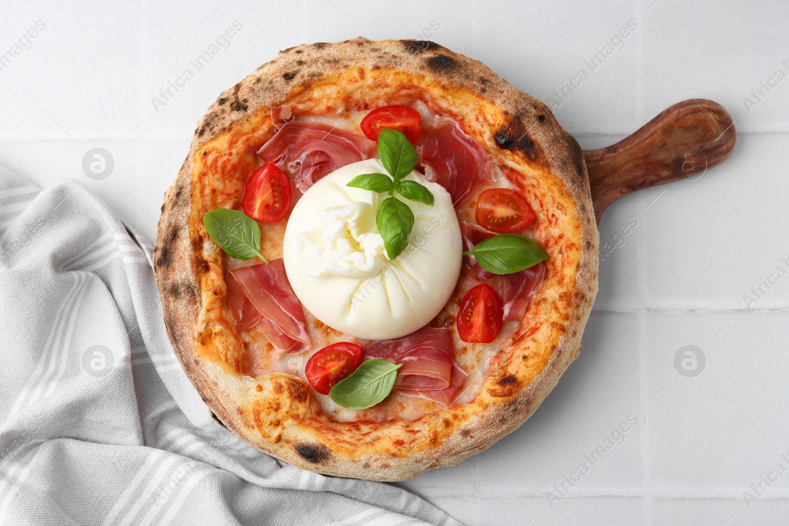 Photo of Delicious pizza with burrata cheese, basil, tomato and ham on white tiled table, top view