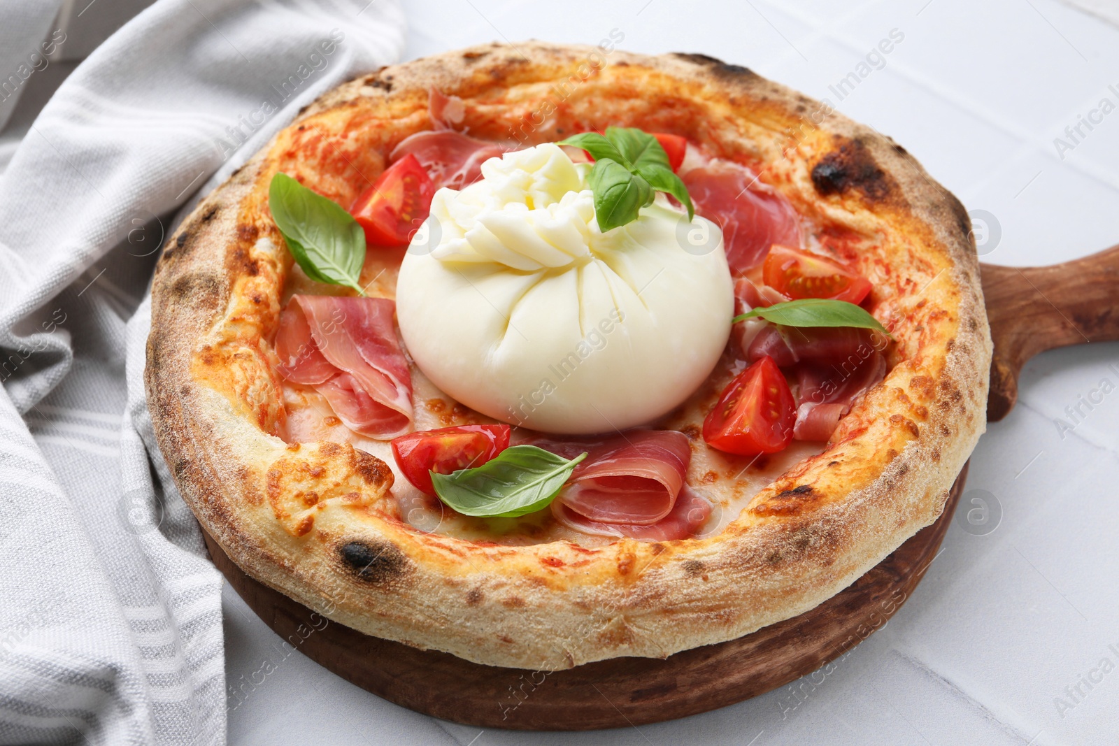 Photo of Delicious pizza with burrata cheese, basil, tomato and ham on white table, closeup