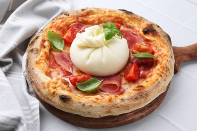 Delicious pizza with burrata cheese, basil, tomato and ham on white table, closeup