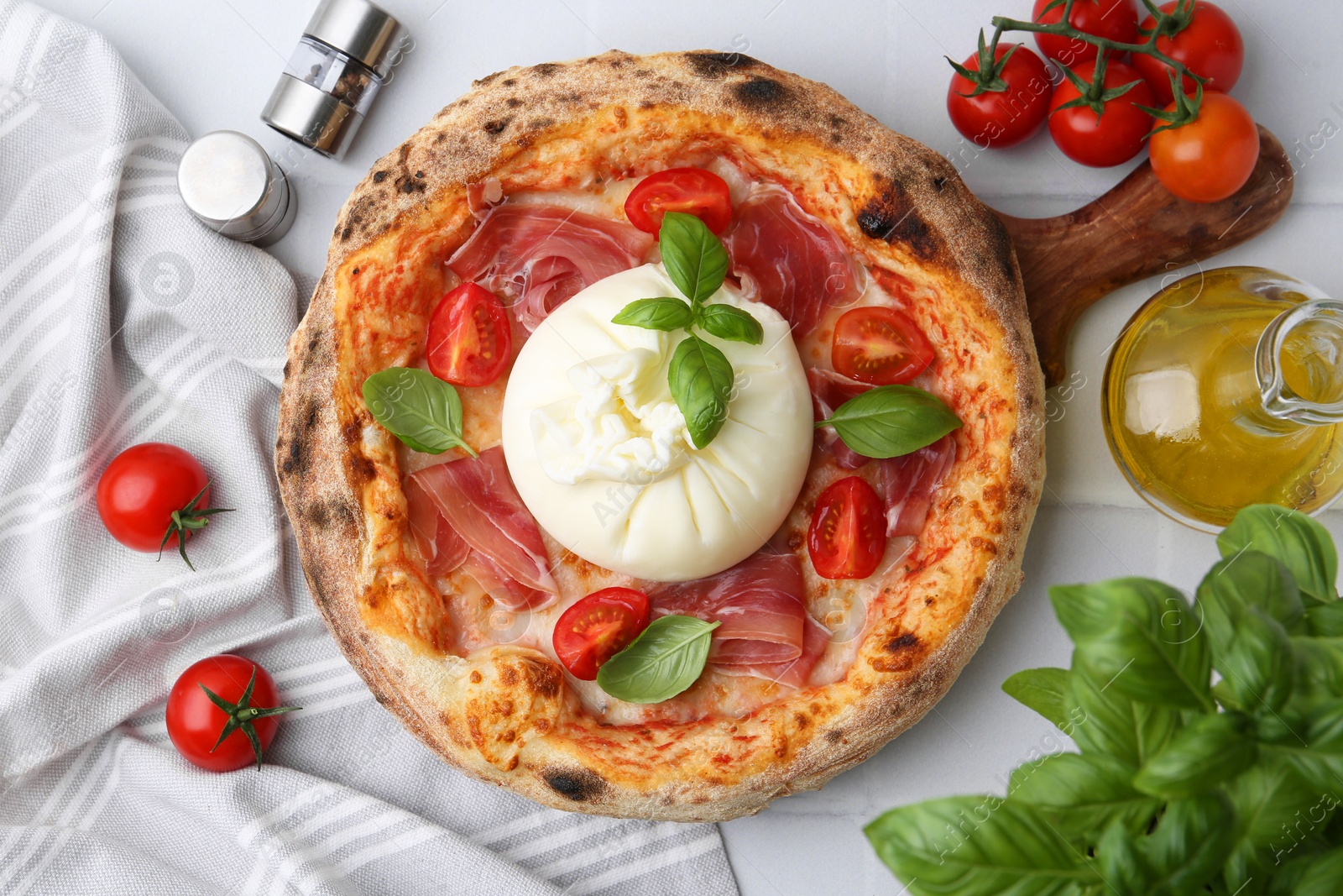 Photo of Delicious pizza with burrata cheese, basil, tomatoes and ham on white table, top view