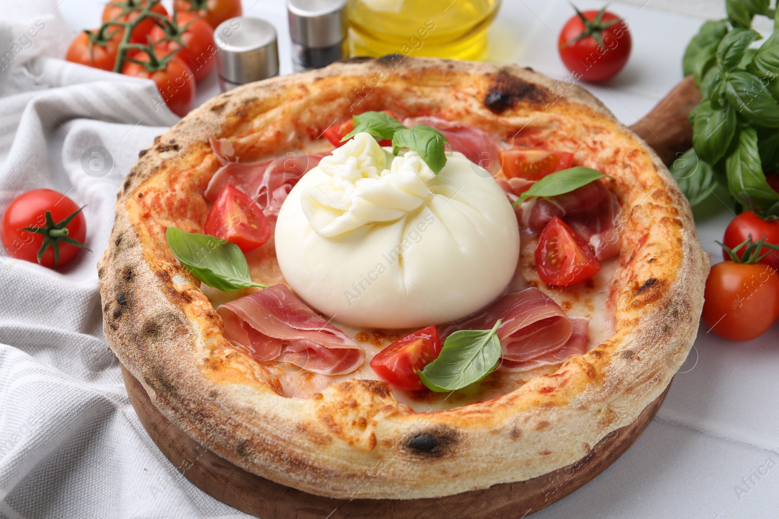 Photo of Delicious pizza with burrata cheese, basil, tomatoes and ham on white table, closeup