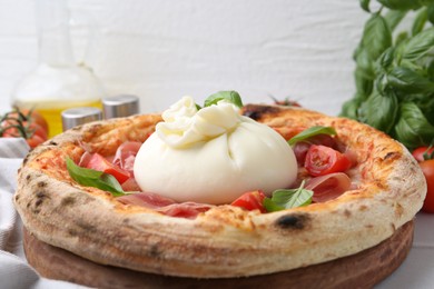 Photo of Delicious pizza with burrata cheese, basil, tomatoes and ham on table, closeup