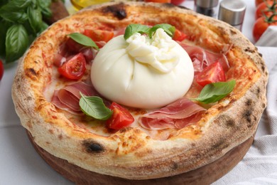 Photo of Delicious pizza with burrata cheese, basil, tomato and ham on table, closeup