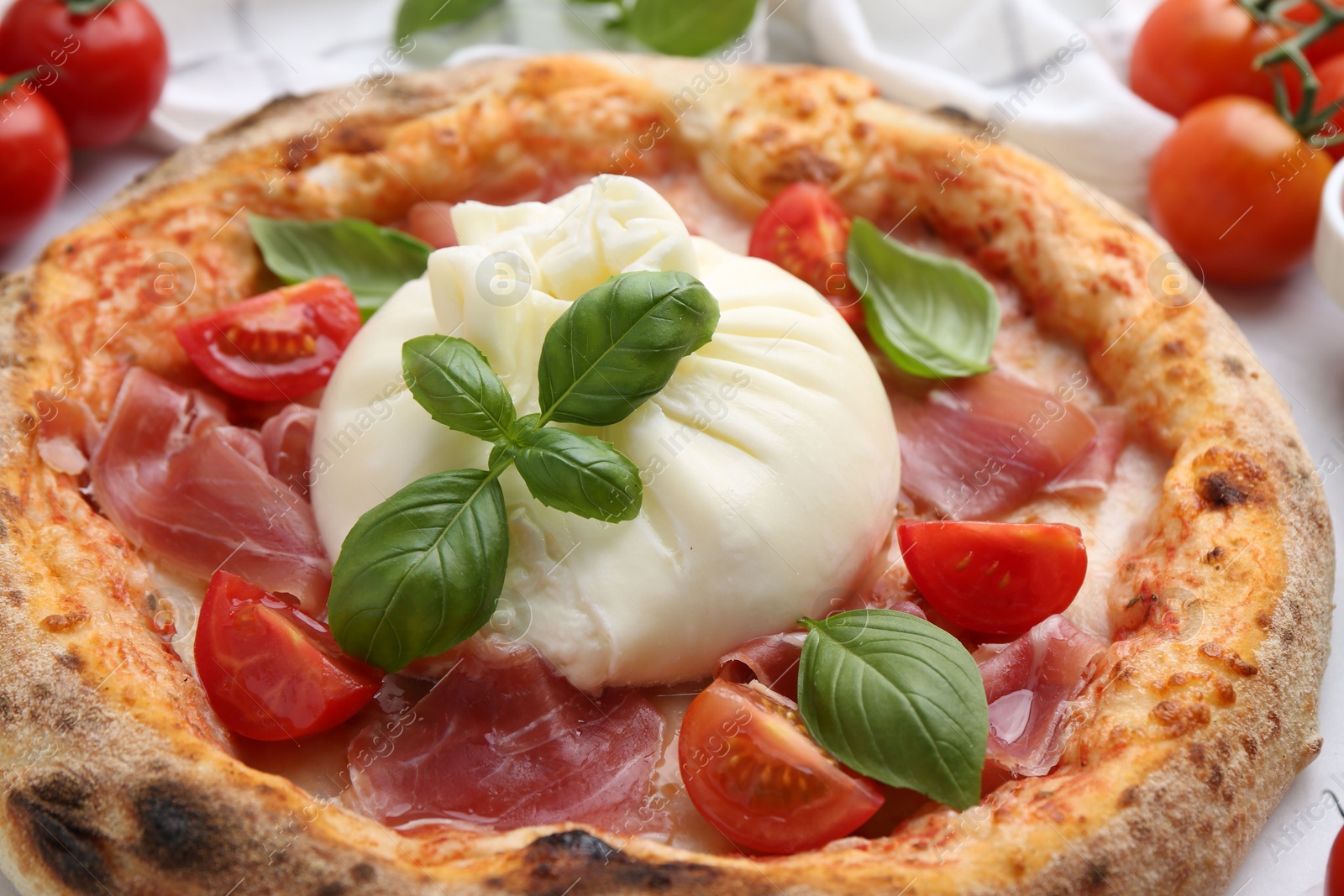 Photo of Delicious pizza with burrata cheese, basil, tomato and ham on table, closeup